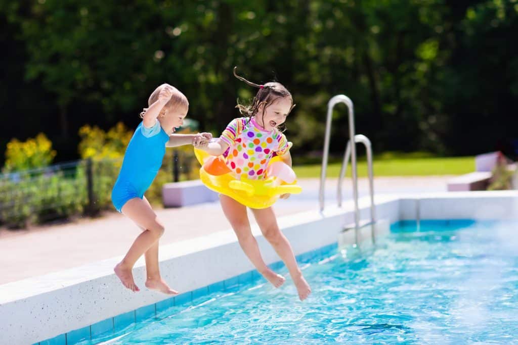 boy and girl mid air, jumping into a pool