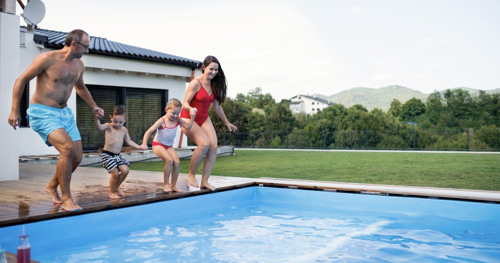 Family of four holding hands while jumping into a pool
